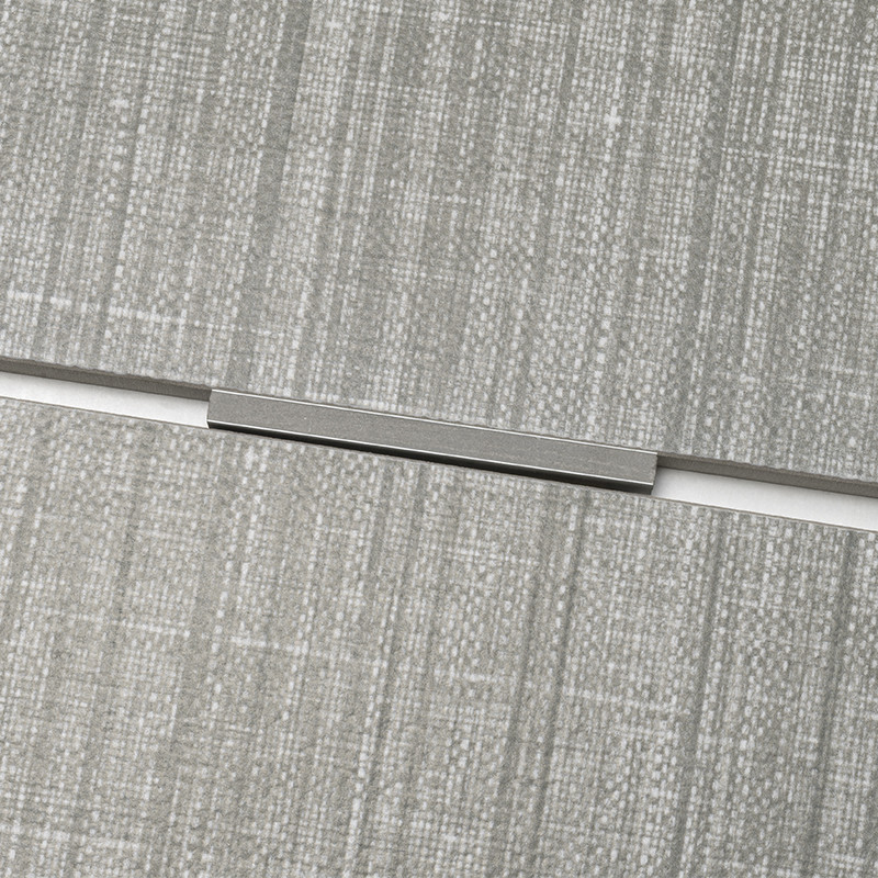 Azulejo texturizado gris claro con patrón tipo tela; junta horizontal estrecha rematada por un separador metálico rectangular; contexto: paneles adyacentes alineados formando una superficie continua.
