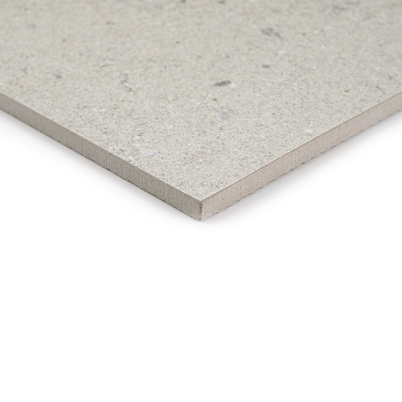 Carrelage gris clair à fini légèrement granuleux, coin biseauté montrant l'épaisseur de la dalle, posé sur un fond blanc neutre.