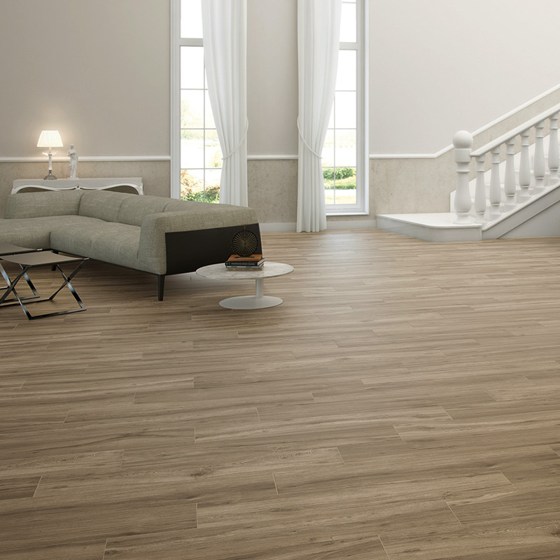 Carrelage effet bois clair couvrant un vaste salon contemporain; canapé gris, petites tables rondes blanches, lampe, grandes fenêtres avec rideaux, escalier blanc à rampe balustrade.