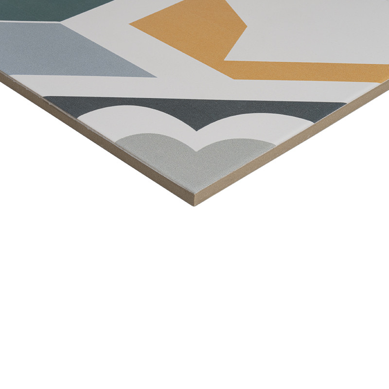 Fliese mit geometrischem Muster (Gelb, Türkis, Grau, Weiß, Schwarz); sichtbare abgeschrägte Kante und Schnittfläche, freigestellt vor weißem Hintergrund.