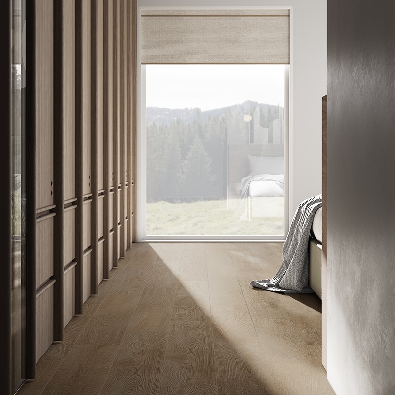 Bodenfliese in Holzoptik, hellbraun; langer Korridor mit Einbauschränken links, Bett rechts; großes Fenster mit Rollo zeigt Bergwiese; diagonales Sonnenlicht fällt auf den Boden.