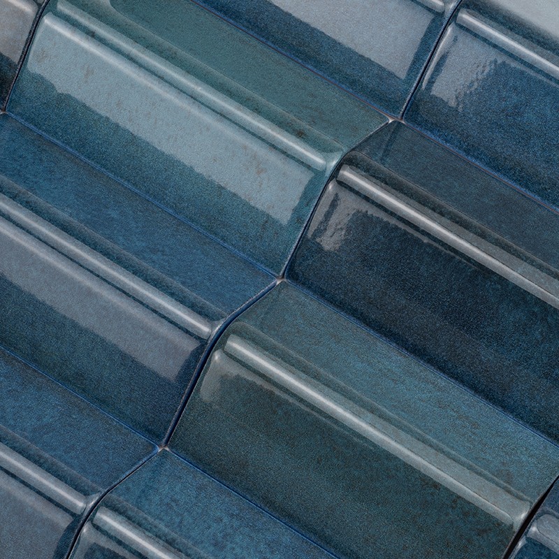 Rectangular ceramic tiles glazed in shades of blue-green with curved relief; arranged in a stepped pattern forming bright and reflective rows.