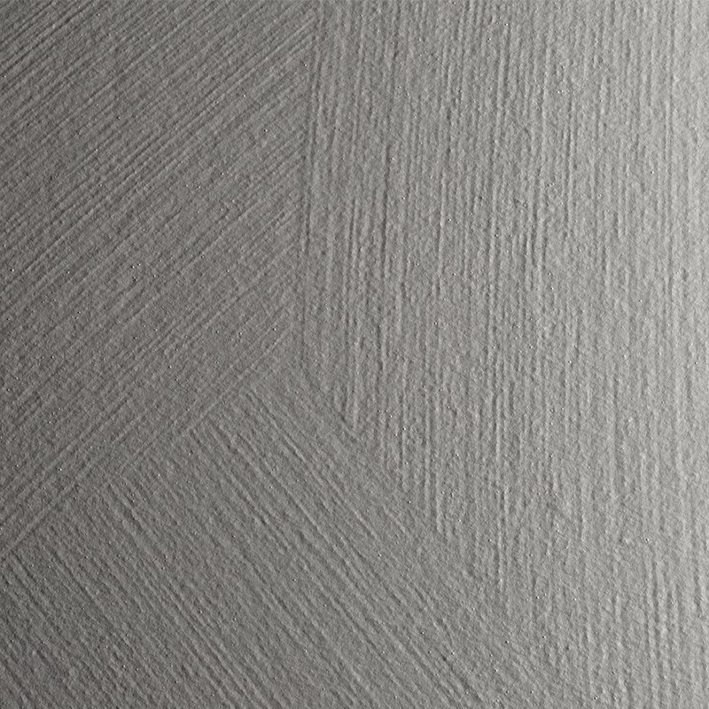 Azulejo gris claro texturizado con estrías diagonales que forman patrones angulares; superficie mate con ligera junta vertical central que sugiere unión entre piezas.
