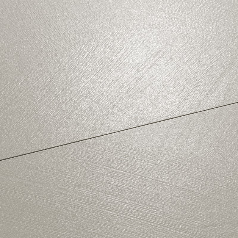 Azulejo claro texturizado dividido por una junta diagonal; superficie cremosa y ligeramente rugosa con finas marcas circulares, iluminación suave y uniforme.