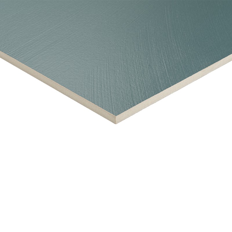 Tegel met groen‑blauwe, licht gestructureerde bovenzijde en zichtbare beige kern, scherp afgewerkte rand en dun profiel, gedeeltelijk afgebeeld tegen een witte achtergrond.