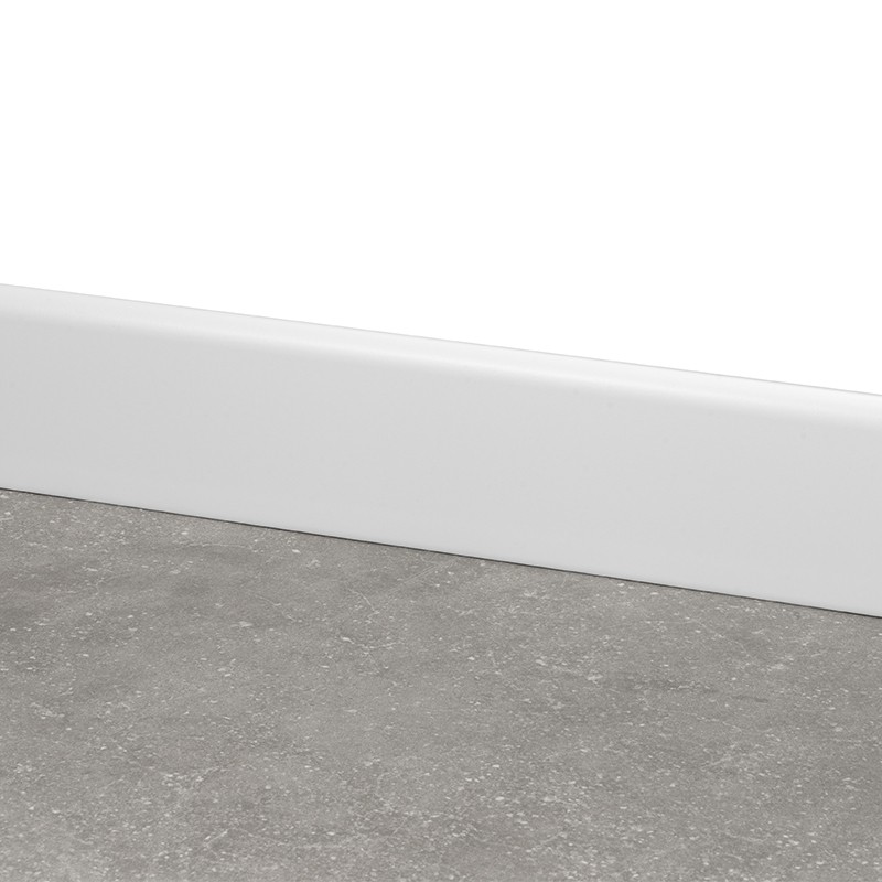 Graue, leicht strukturierte Bodenfliese in Betonoptik vor einer weißen Sockelleiste und glatter weißer Wand.