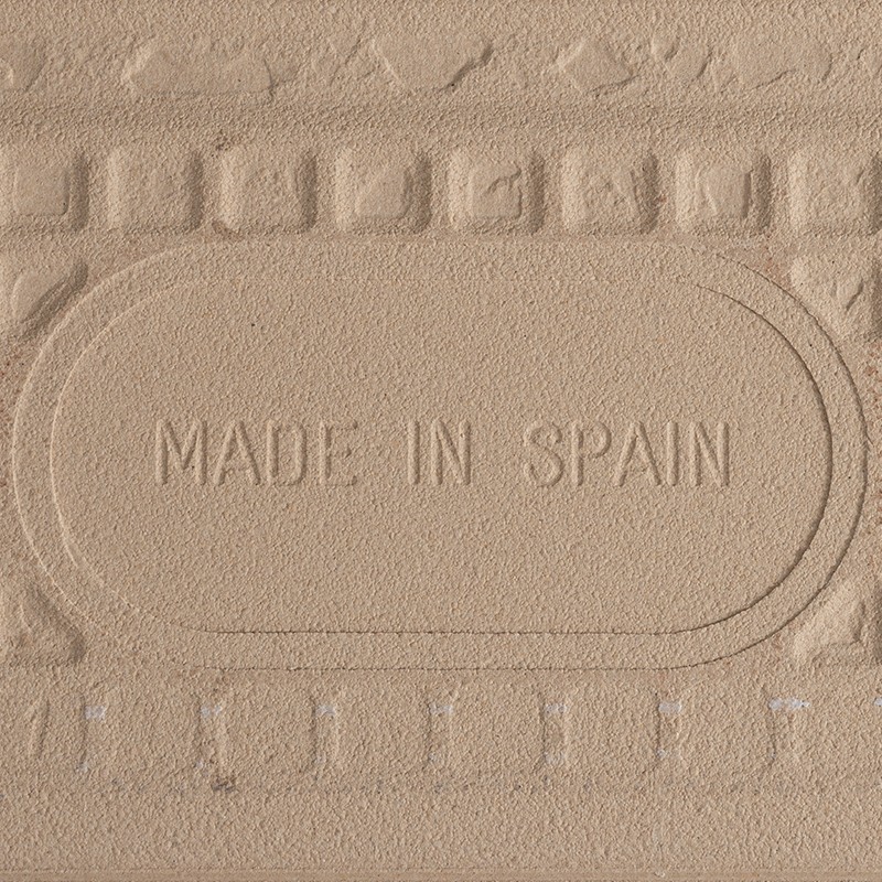 Carrelage beige texturé, inscription embossée "MADE IN SPAIN" au centre; bordure moulée décorative entourant le panneau.