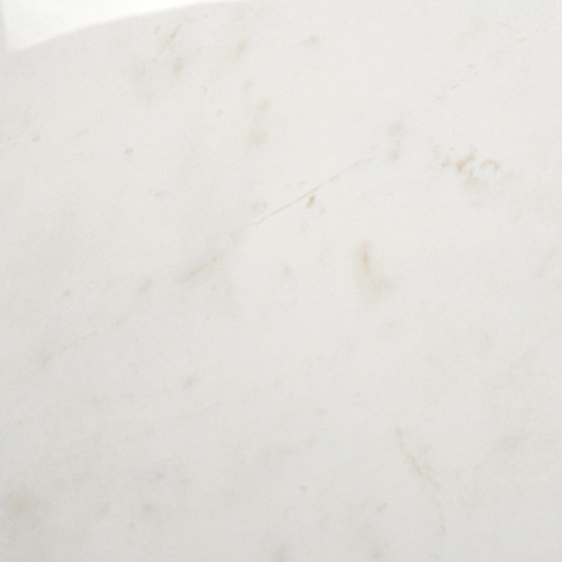 Carrelage blanc crème à fines veines beige et petites taches, surface lisse et légèrement marbrée; sans autres éléments visibles.