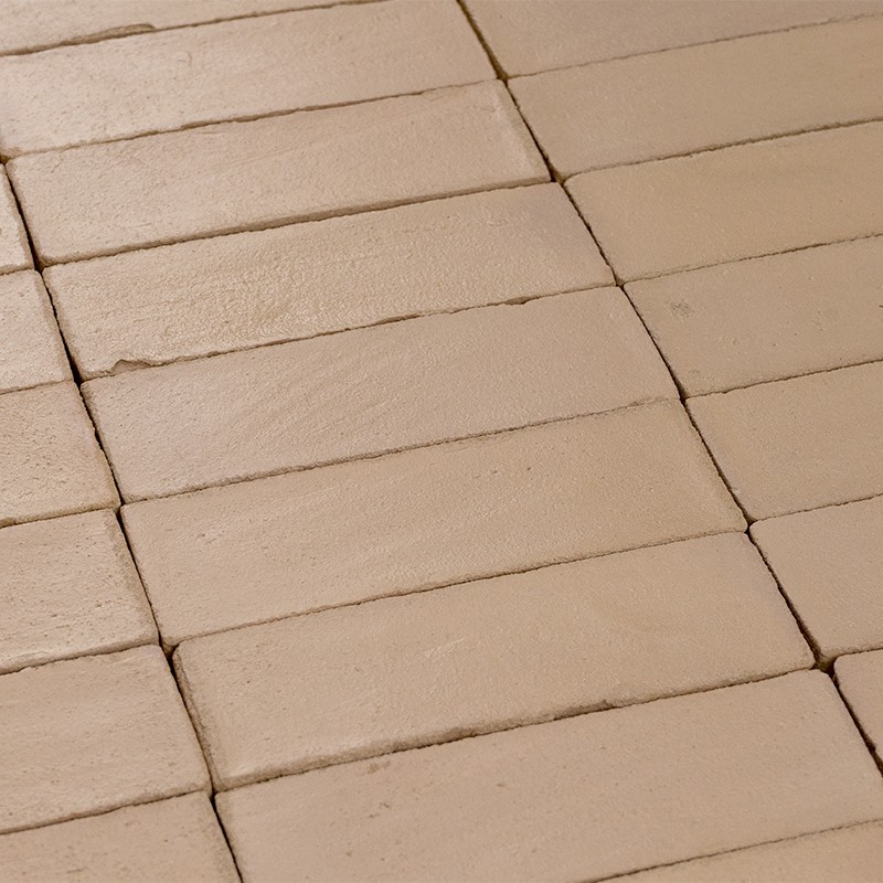 Azulejos rectangulares beige dispuestos en hileras regulares; juntas finas, superficie mate y levemente rugosa, cubriendo un suelo plano.