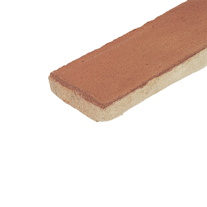 Carreau rectangulaire allongé, dessus terre cuite rouge-brun et base crayeuse beige, bords biseautés, incliné sur fond blanc.
