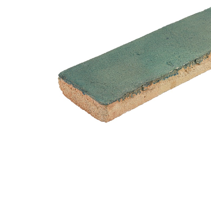 Rectangular green tile, glazed and worn top edge, visible beige ceramic edge and base; placed on its edge on an isolated white background.