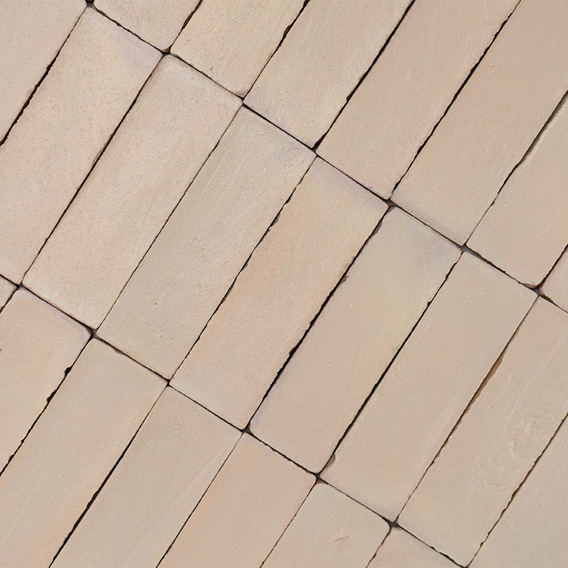 Beige rechteckige Fliesen (Wand/Boden), diagonal verlegt; glatte, leicht strukturierte Oberflächen mit schmalen dunklen Fugen, gleichmäßige warme Farbgebung.