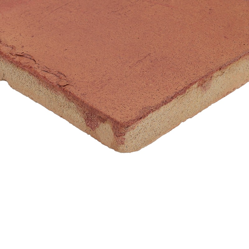 Terracotta tile, corner and edge visible, reddish surface with rough texture; cut shows light sandy core; on neutral white background.