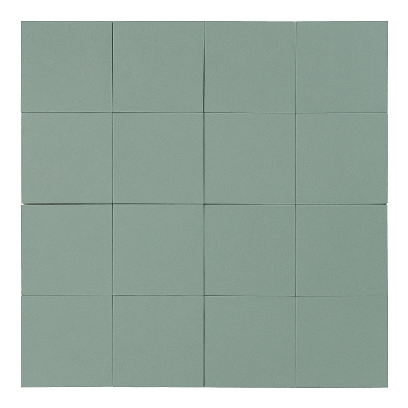 Azulejo cuadrado verde grisáceo, textura lisa con micrograno; centrado sobre fondo blanco amplio, sombra sutil en el borde inferior que sugiere separación del soporte.