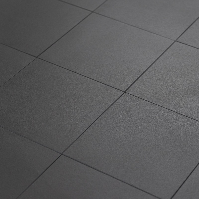 Carrelage carré foncé mat; sol intérieur, joints fins et réguliers, surface légèrement granuleuse, éclairage uniforme créant perspective diagonale avec plusieurs dalles visibles.