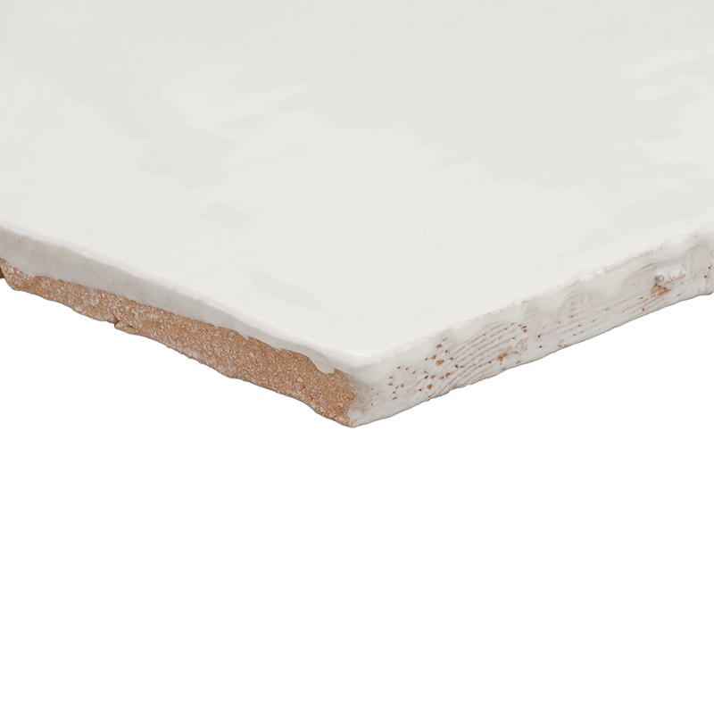 White glazed tile, beveled corner showing brown ceramic core and glaze layer; neutral white background, close focus highlighting texture, thickness and edge.