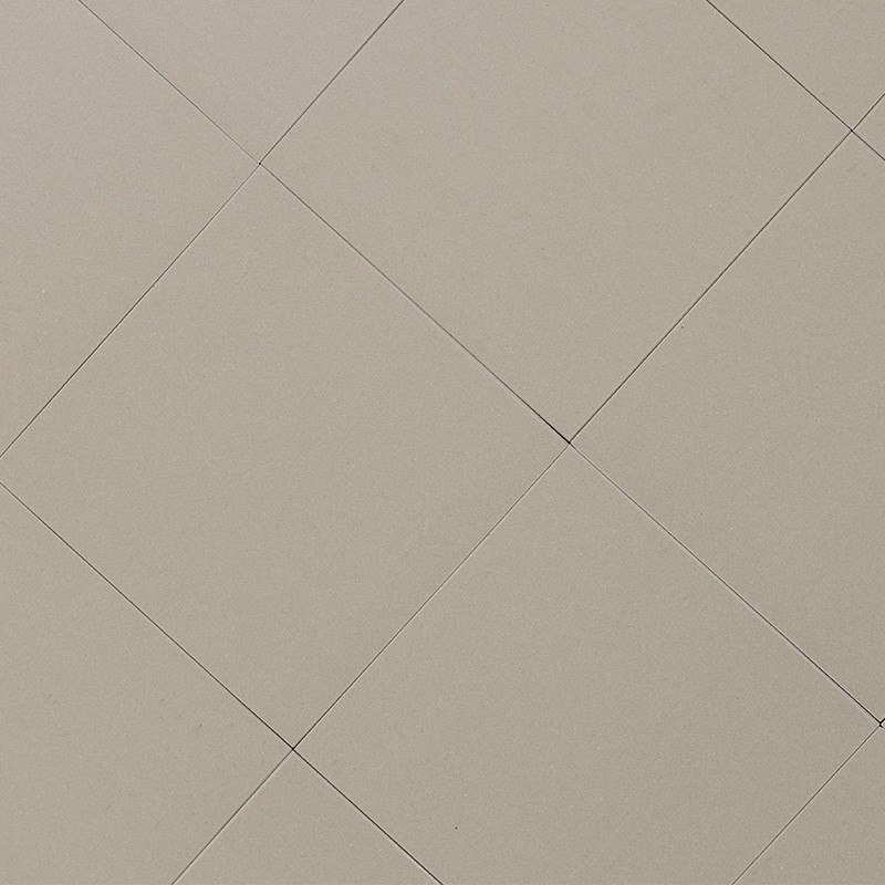 Quadratische beige Fliesen, glatte matte Oberfläche; dünne dunkle Fugen kreuzen diagonal und bilden regelmäßiges, sich wiederholendes Rautenmuster.