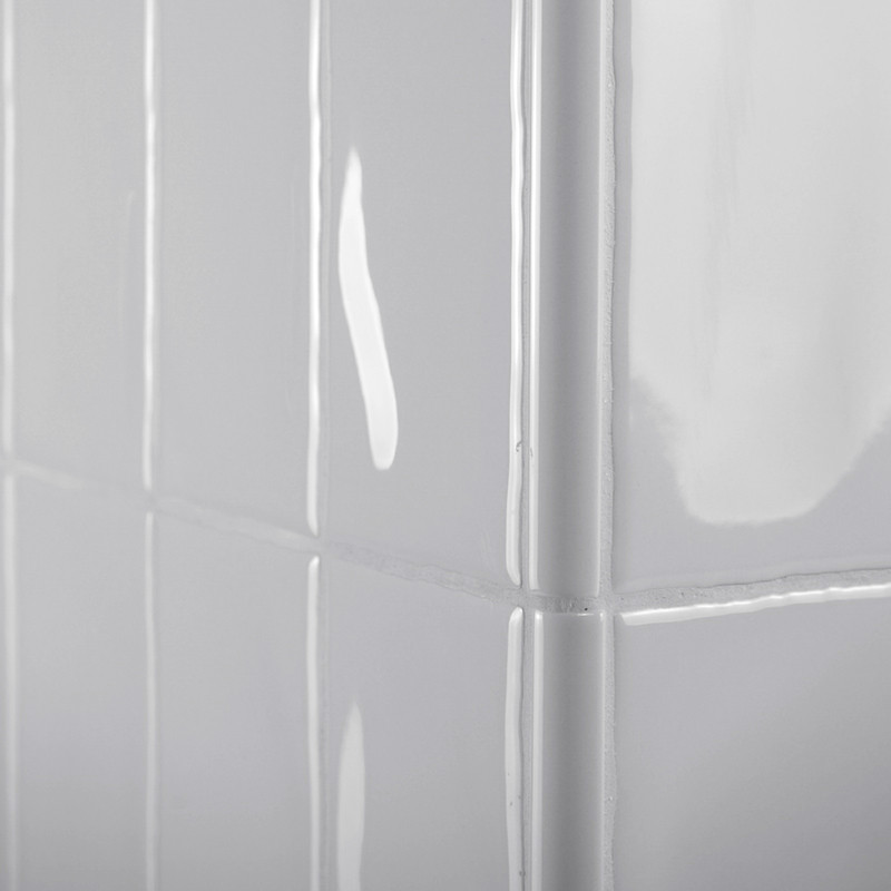 Glanzende witte rechthoekige tegels bedekken een hoekmuur en reflecteren het licht in een glad, netjes rasterpatroon.