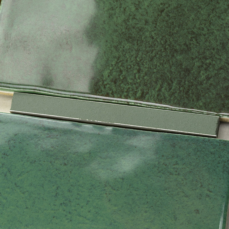 Green ceramic tiles with a glossy finish overlap slightly, showcasing variations of dark and light green hues, forming a texture