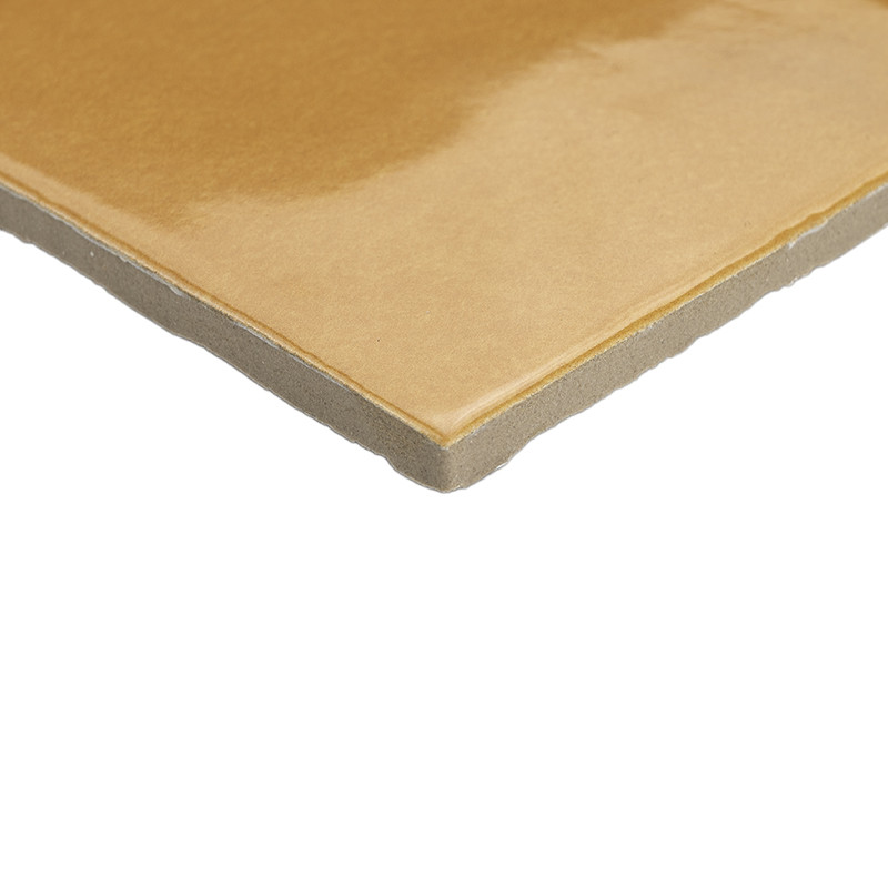 Carreau beige brillant, coin visible, noyau gris épais et bord légèrement chanfreiné; présenté en gros plan sur fond blanc, mettant en évidence l'épaisseur et la finition.