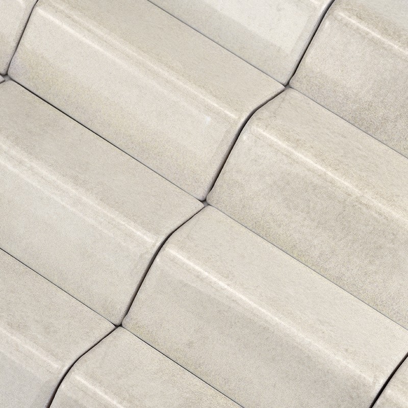Azulejos rectangulares cerámicos color crema con bordes curvados; dispuestos en patrón repetido en filas superpuestas, con juntas estrechas y superficie ligeramente moteada.